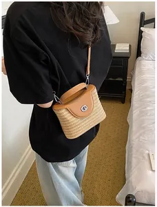 Sac seau en paille tissée avec rabat en cuir beige porté par un mannequin de dos
