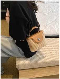 Sac seau en paille fait main avec rabat en cuir marron porté en bandoulière en situation