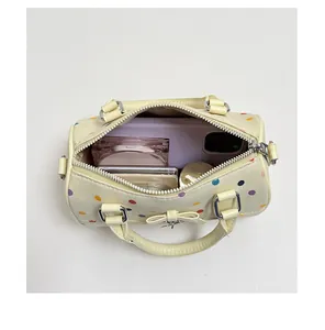 Detalle de la capacidad interna de un mini bolso cilíndrico de lunares de colores
