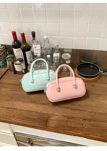 Vue détaillée de sacs de bowling en cuir vert menthe et rose sur un comptoir de cuisine.