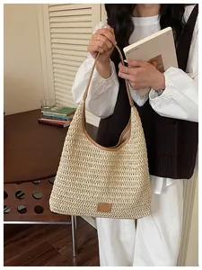 Dettaglio borsa a spalla in paglia intrecciata, hobo estiva elegante con finiture in pelle.