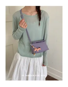 Borsa a tracolla viola minimalista con un simpatico ciondolo a forma di pony su modella.