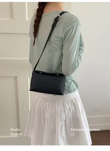Dettaglio della borsa a tracolla nera testurizzata abbinata a un outfit minimalista