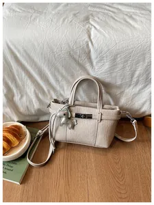 Detailed view of beige textured commuter handbag with a horse charm and twist lock.