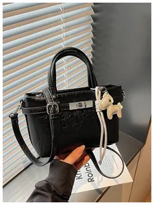 Detailed macro view of a black crinkled leather mini tote bag with a white horse charm