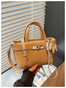 Close-up of tan pebbled leather handbag with elephant charm and twist-lock