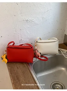 Dettaglio di borse a tracolla minimaliste rosse e bianche con ciondoli a forma di cavallo.