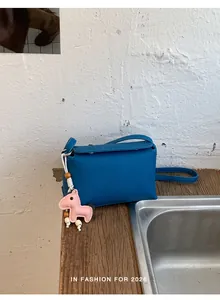 Vista dettagliata di una borsa a tracolla in pelle blu con un grazioso ciondolo a pony rosa.