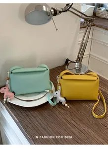 Dettaglio di borse a tracolla verde menta e giallo con simpatici ciondoli a cavallo.