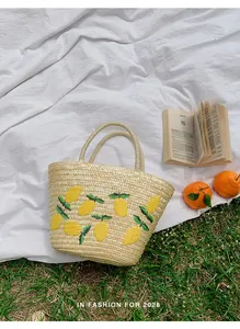 Detail van handgemaakte strooien strandtas met geborduurd citroenpatroon tijdens picknick