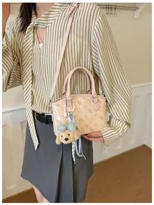 Chic pink shoulder bag for women, cute cartoon print crossbody design with plush dog pendant.