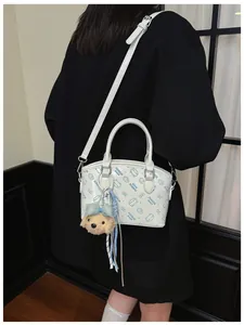 Detailed view of white crossbody bucket bag with cartoon print and cute plush bear charm.