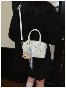 Detailed view of trendy women white crossbody handbag featuring cute cartoon print and plush charm.