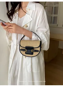 Lifestyle detail of a chic straw saddle bag with black leather trim and gold buckles.