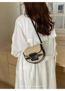 Detailed view of a woven straw saddle bag with black leather trim on a model