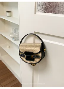 Woven straw saddle bag with black leather trim hanging in a minimalist home setting