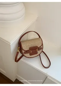 Detailed view of the woven straw saddle bag with sophisticated brown leather trim and retro vibe