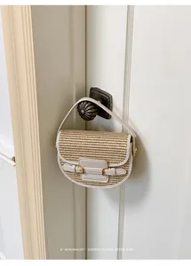 Elegant straw woven saddle bag with leather trim hanging on a vintage door handle