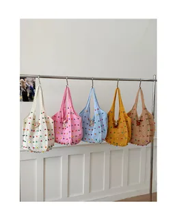 Bolsos de mano de ganchillo de varios colores con cuentas en un soporte.