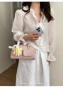Close-up of elegant pink Boston handbag with a cute rabbit charm in a lifestyle setting