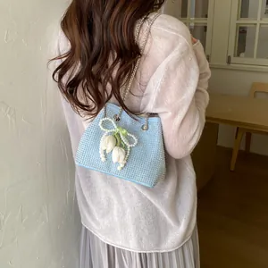 Detailed view of the light blue rhinestone bucket bag with pearl and tulip charms, elegant chain.