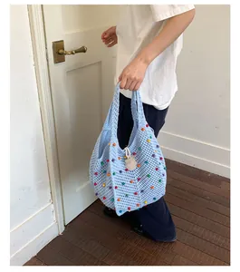 Bolso de punto calado azul con cuentas de colores mostrado en un entorno de interior