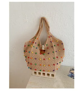 Bolso de playa grande de punto boho con cuentas de colores sobre fondo de piedra
