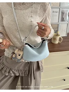 Vintage style women bucket bag detailed view, elegant leather shoulder strap and bear charm.