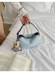Chic light blue bucket bag detail shot showcasing contrast stitching and cute bear pendant.