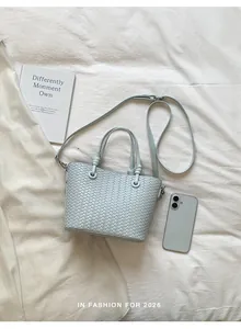 Elegant light blue woven leather shoulder bag with chic knotted handles for women.