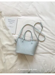 Elegant light blue woven bucket bag with top handle and crossbody strap for women.