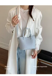 Detail view of a light blue woven bucket bag featuring a refined cross-weave texture