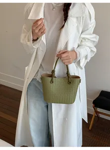 Detail shot of green woven leather bucket bag with knotted handle, elegant daily fashion accessory.