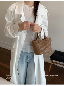 Sophisticated brown woven bucket bag styled with a white trench coat and blue jeans