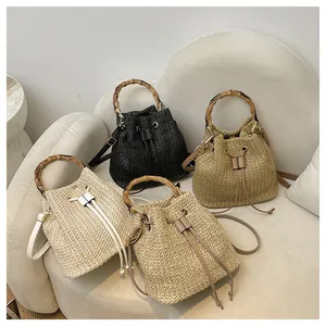 Vue détaillée de sacs seau en paille tendance avec poignées en bambou pour la plage.
