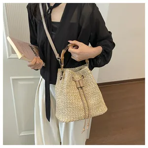 Sac seau en paille pour femme, élégant sac tissé avec poignée en bambou et bandoulière réglable.