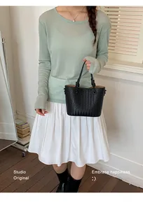 Close-up detail of a minimalist black woven bucket bag being held by a model.