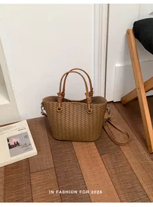 Detailed view of a brown woven bucket bag featuring elegant top handles and strap