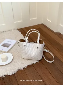 Detailed view of an elegant white woven bucket bag with handles in a home setting