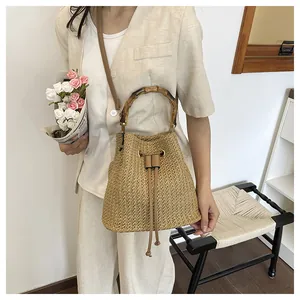 Sac seau en paille élégant avec poignée en bambou, design tissé chic pour vacances.