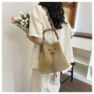 Sac seau en paille avec poignée en bambou naturel, cordon en cuir et design de plage.