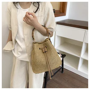Sac seau en paille chic pour femmes avec poignée en bambou, idéal pour les vacances à la plage.