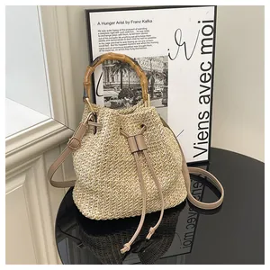 Sac seau en paille élégant avec poignée en bambou et lanière en cuir pour les vacances.