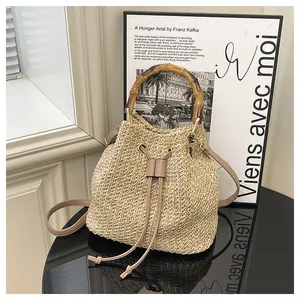 Detail de sac seau en paille avec poignee en bambou et cordon cuir PU pour plage d'ete.