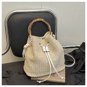 Sac seau en paille tressée élégant avec poignée en bambou pour les vacances à la plage.