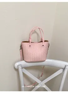 Pink woven bucket bag detail, chic top handle shoulder bag with crossbody strap, stylish mini bag.