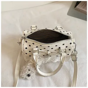 Cream polka dot Boston handbag with lace trim and plush dog charm, striped lining view