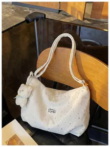 Vista dettagliata della borsa a tracolla bianca con stelle e ciondolo orsetto in peluche.