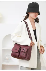 Detailed shot of stylish maroon soft leather shoulder bag with chic pattern strap and pockets.