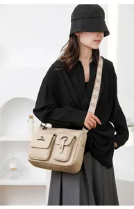 Detail shot of a stylish soft leather shoulder bag with chic front pockets and wide strap.